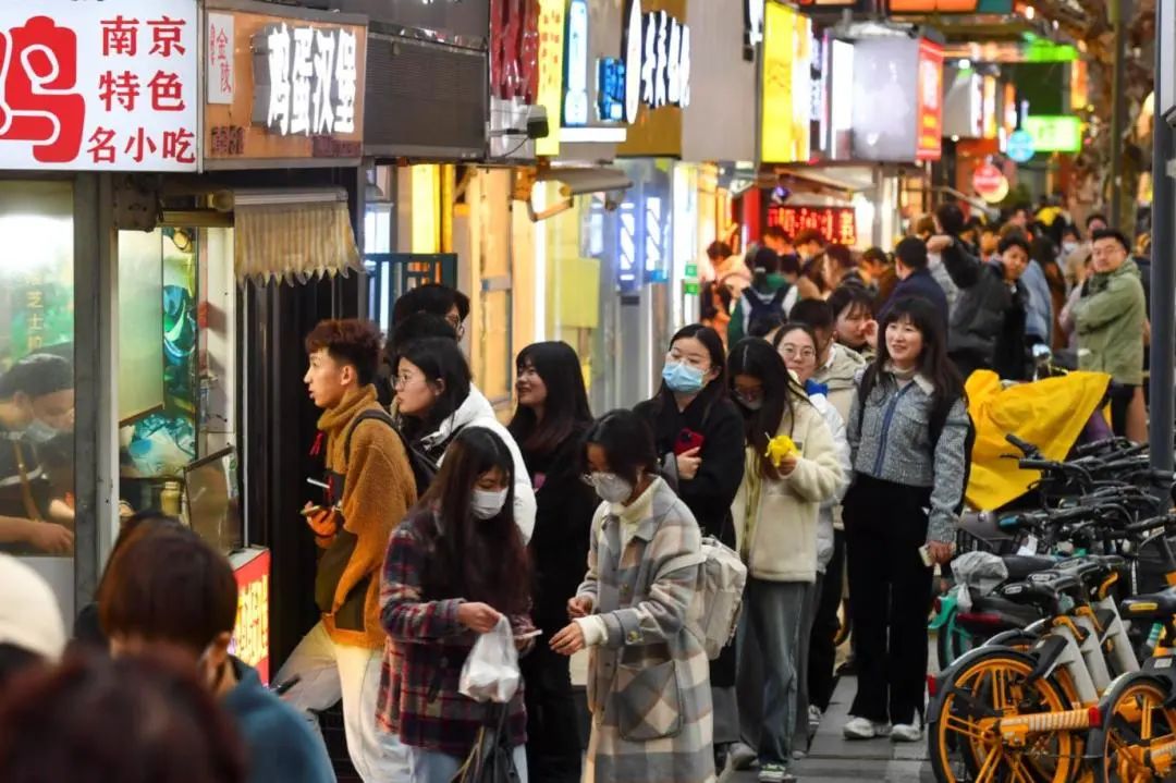 夜幕下的南京丰富路人气火爆，许多游客在此购买美食，烟火气满满。