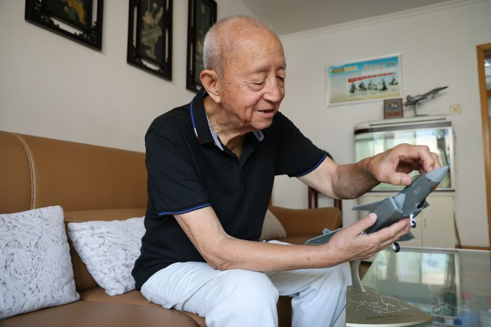 ↑2023年7月24日，新中国第一代飞行员陶伟在家中擦拭歼-20飞机模型。新华社发（张瑞 摄）