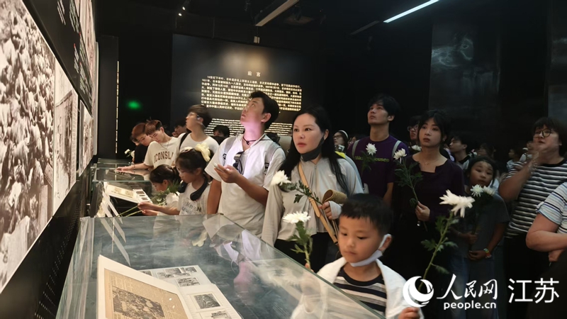 人們手持菊花參觀“南京大屠殺史實展”。人民網 王丹丹攝